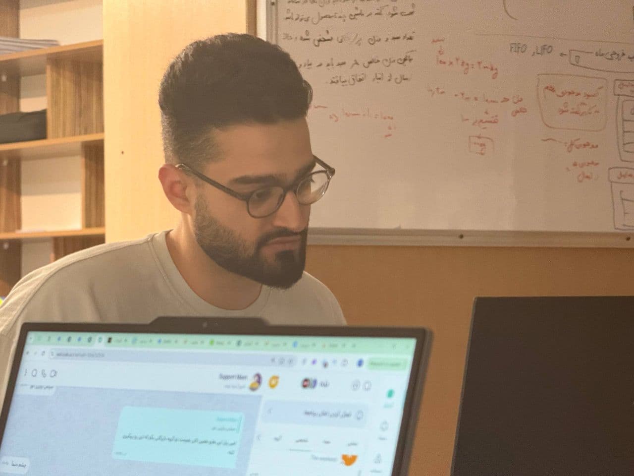 Working at a laptop beside a whiteboard